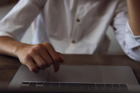 Person is using a laptop, with a hand moving on the touchpad, symbolizing f.. Stock Photos
