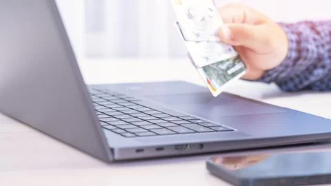 A person is using a laptop to pay for something with a credit card Stock Photos