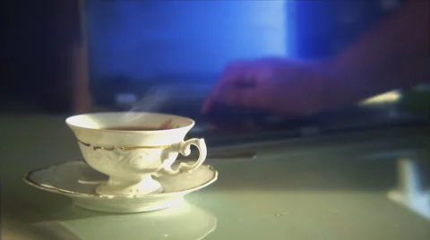 Person using a laptop, with a teacup in the foreground. Shallow focus. Stock Footage 44561383