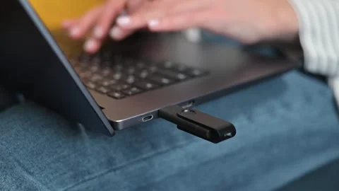 A person is using a laptop to transfer files with a USB drive plugged in. The Vidéo 338446246