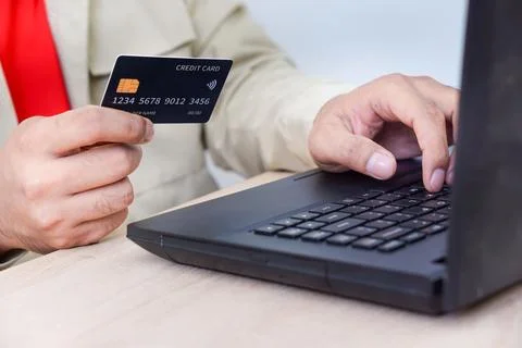 A person using a laptop while holding a credit card, illustrating online sh.. Foto stock