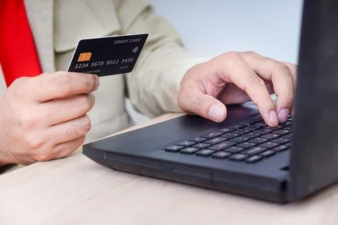 A person using a laptop while holding a credit card, illustrating online sh.. Foto stock