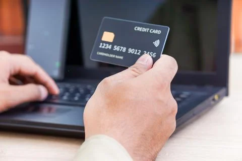A person using a laptop while holding a credit card, illustrating online sh.. Stock Photos