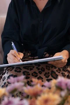 Person using a laptop while sitting on a chair, wearing pink loungewear at home Stock Photos