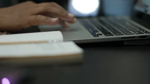 Person Using Laptop While Writing in Notebook at Desk Stock Footage 345102103