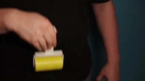Person using a lint roller to clean clothing for a fresh appearance Stock Footage 340265717