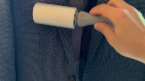 Person Using Lint Roller on Navy Blue Suit Jacket Stock Footage 338198806