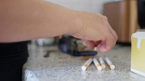 A person is using a machine to roll cigarettes while having tobacco scattered Stock Footage 313631209