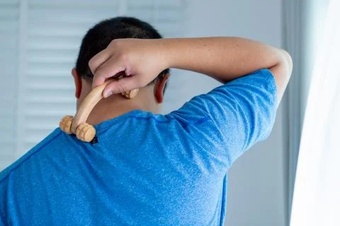 Person using a massage tool for back pain relief and self-care in a home se.. Fotos de archivo