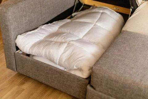 A person is using a mattress topper placed on the sofa for a good night sle.. Stock Photos