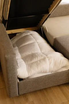 A person is using a mattress topper placed on the sofa to sleep comfortably.. Stock Photos