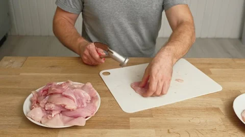 Person using meat tenderizer on raw chicken. Chef preparing pork loin slice with Stock Footage 324197585