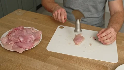 Person using meat tenderizer on raw chicken. Chef preparing pork loin slice with Stock Footage 324198690