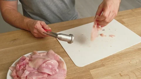 Person using meat tenderizer on raw chicken. Chef preparing pork loin slice with Stock Footage 333464023