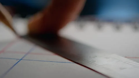 Person using a metallic ruler to draw lines on a piece of paper Stock Footage 274583496