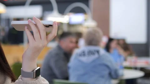 Person using mobile device in modern cafe, capturing moments Stock Footage 342028821