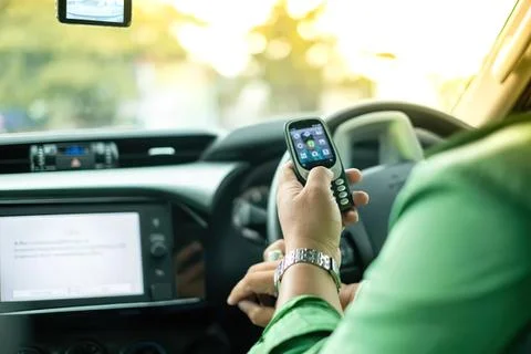 Person using mobile phone in car while driving on road Stock Photos