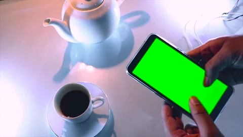 A Person is Using a Mobile Phone With a Green Screen On a Tea Set Background Video stock 170154601