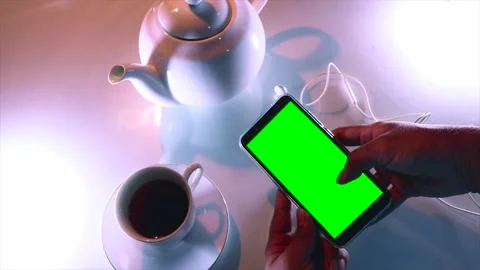 A Person is Using a Mobile Phone With a Green Screen On a Tea Set Background. Stock Footage 170154636