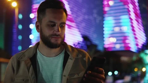 Person using mobile smartphone outdoors at night city with neon lights buildings Video stock 211769830