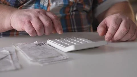 Person using a number pad at a table with receipts and a check nearby in an Stock Photos