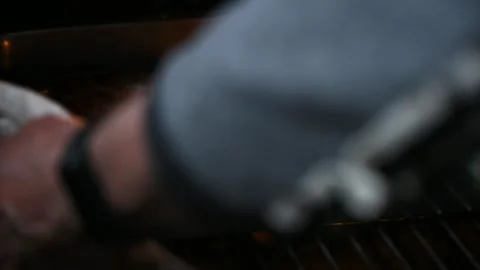 Person using oven mitt to remove roasting pan with sausages from hot oven Stock Footage 337239984