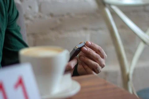 A person is using the phone in a cafe. Stock Photos