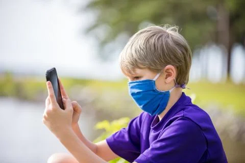 Person using phone while wearing face mask during covid19 pandemic Stock Photos
