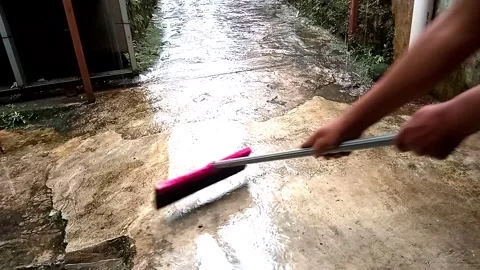 Person using pink floor squeegee to clear water after rain Video stock 334772366