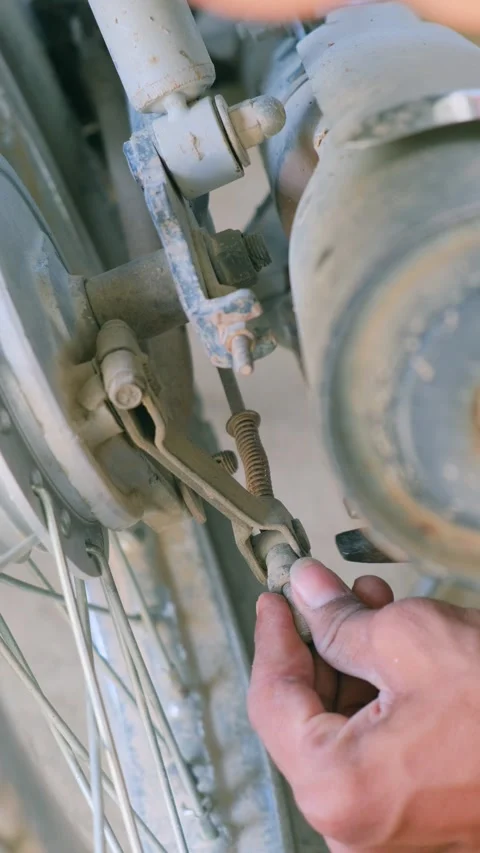 A person using pliers to adjust the rear drum brake cable of a motorcycle 스톡 동영상 332997838