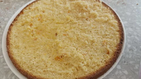 A person using a red silicone brush to soak a sponge cake layer with syrup Stock Footage 330398278