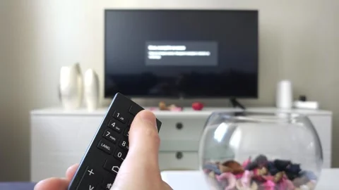 Person using remote control to operate television in a modern living room Stock Footage 297610963