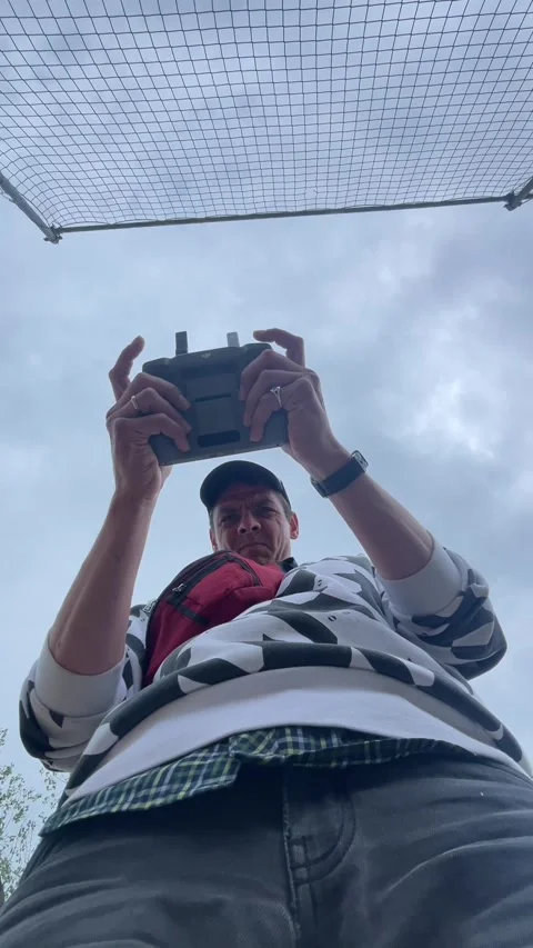 Person using remote controller beneath mesh safety net, viewed from low angle Stock Footage 344584541