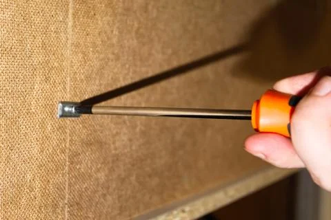 A person using a screwdriver to fasten hardware to a textured wall in a hom.. Stock Photos