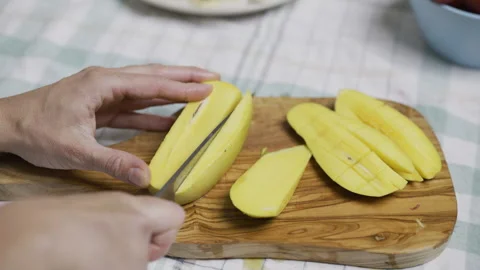 Person using sharp knife to cut up squares into mango slices, closeup Stock Footage 341237568