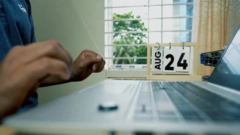 Person using a small mechanical device with cards near a laptop Stock Footage 315982682