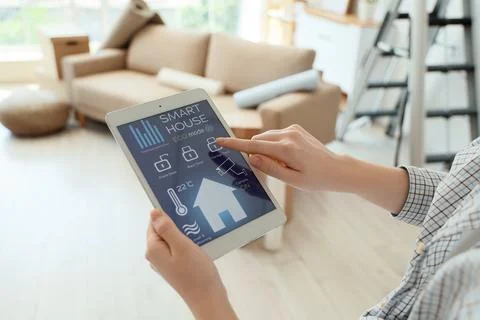 Person using a smart home system on a digital tablet to control security and  Stock Photos