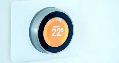 A person using a Smart Thermostat with a hand setting lower the temperature savi Stock Footage 128279232