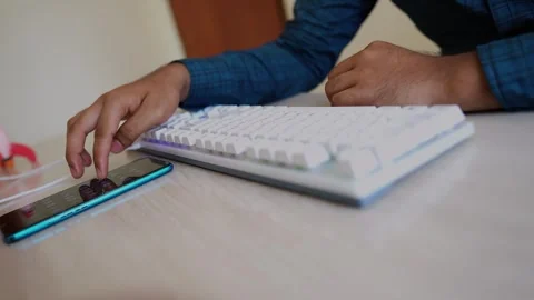 Person Using Smartphone and Keyboard at Desk Stock Footage 317736525