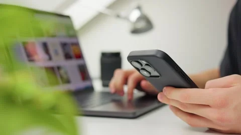 Person using smartphone and laptop at modern bright workspace Stock Footage 320317942