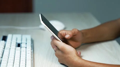 Person using smartphone beside computer keyboard, Close view of a person ho.. Vídeos de archivo 346484242