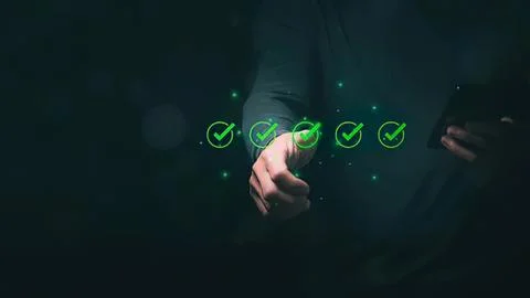 Person using smartphone with checkmarks on screen in dark Stock Photos