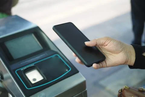 A person using a smartphone for a contactless NFC scan at a public transit Stock Photos