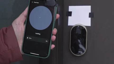 Person using smartphone to control smart lock on front door, showing unlocking Stock Footage 332578498