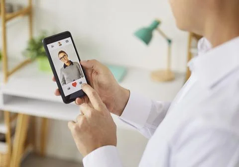 Person using smartphone dating app to like a profile with heart icon closeup Stock Photos