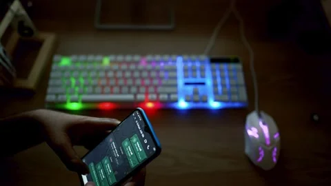 Person using a smartphone with a gaming keyboard and mouse on a desk Stock Footage 315982453