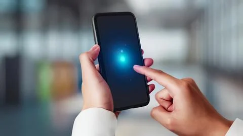 Person using smartphone with glowing screen in modern space Stock Photos