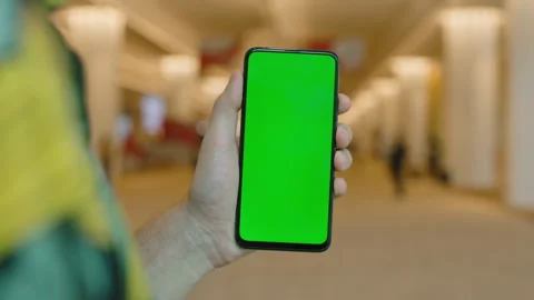 Person using smartphone with green screen in blurred modern interior Stock Footage 310182567