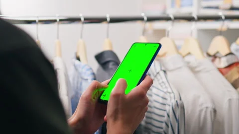 Person using smartphone with green screen background in a clothing store whi Stock Footage 323714329