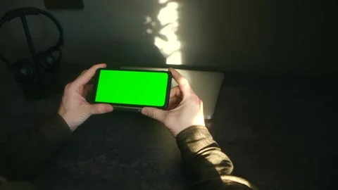Person using smartphone with green screen at desk 스톡 동영상 337827421